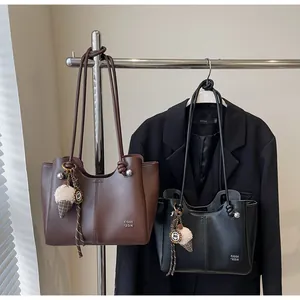Detail of coffee brown and black leather tote bags with plush ice cream charms