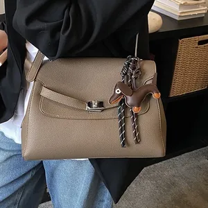 Brown leather trapezoid handbag with silver twist lock and dachshund charm in a street style