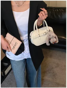 Fashionable beige Boston handbag with silver hardware and plush rabbit charm decor