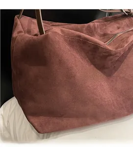 Detail of reddish-brown frosted tote bag with metal zipper and leather shoulder straps