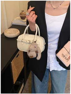 Detail of off-white leather handbag with buckle decor and plush bunny charm accessory