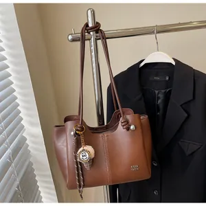 Close-up of deep brown leather tote bag with unique knot detail and metal bead decoration