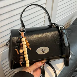 Glänzende schwarze Lederhandtasche mit Perlenanhänger und silberner Schnalle für Damen