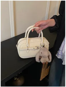 Detail of a creamy white retro square bag with a silver buckle and grey plush bunny charm
