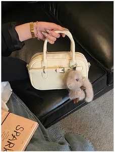Detail view of cream vintage crossbody bag with silver buckle and plush bunny charm