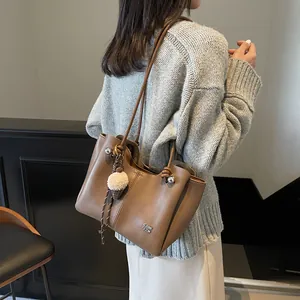 Brown leather commuter tote bag with fur charm shown on a shoulder in winter outfit