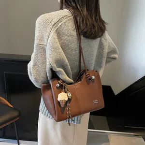 Large capacity dark brown leather tote bag with white lettering and plush charm accessory