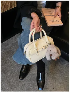 Close-up of cream textured leather handbag with silver buckle and plush rabbit charm