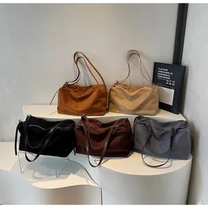 Five matte leather tote bags in assorted autumn colors displayed on a minimalist white stand