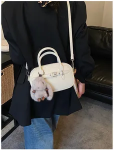 Detail of a beige leather shoulder bag with silver buckle and plush rabbit charm
