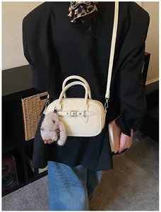 Chic cream leather handbag featuring a plush bunny charm and adjustable crossbody strap