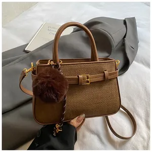 Close-up of vintage brown bucket bag with gold buckle and plush charm detail