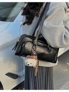 Detail of black leather bowling bag with gold hardware and a cute white puppy pendant