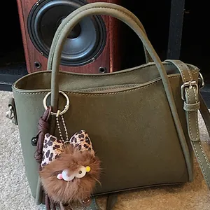 Petit sac à main carré vert olive avec un charmant pendentif de monstre en peluche marron