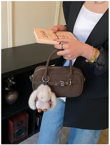 Deep brown matte leather bag with metal buckle detail and plush rabbit pendant
