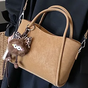 Sac à main chic en similicuir marron avec breloque en peluche et détails argentés
