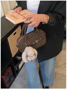 Detail of a dark brown square handbag with a cute plush rabbit charm and metal buckle