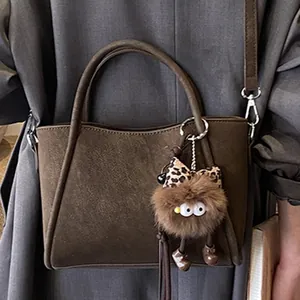Sac fourre-tout en cuir mat café profond avec breloque monstre en peluche et bandoulière