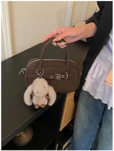 Detail of dark brown vintage Boston bag with a silver buckle and plush bunny charm