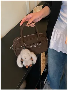 Detail of dark brown leather Boston bag with decorative buckle and plush rabbit charm