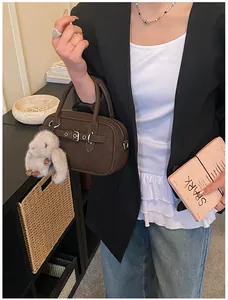 Detail of dark brown cylindrical handbag with plush bunny charm and silver buckle