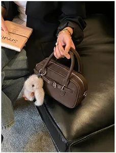 Detail of dark brown matte leather Boston bag with belt buckle and plush rabbit charm