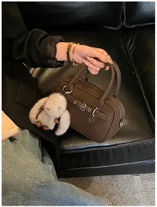 Detailed macro view of dark brown leather Boston bag with metal buckle and plush rabbit charm