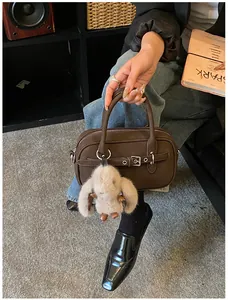 Detail of dark brown vintage bowling bag with silver buckles and plush bunny charm