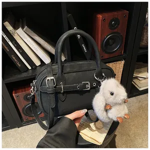Close-up of black crossbody bag with matte finish and cute white rabbit charm accessory