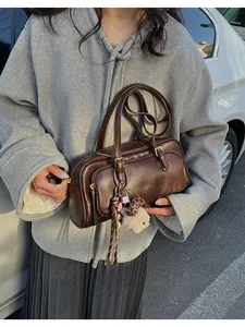 Close-up of deep brown leather bowling bag with cute plush charms and metal zipper