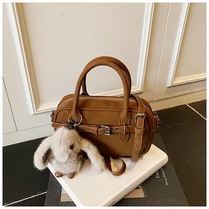 Detail view of brown faux leather mini bag with silver buckle and cute rabbit charm
