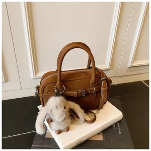 Close-up of vintage brown leather handbag with cute rabbit plush charm and belt detail