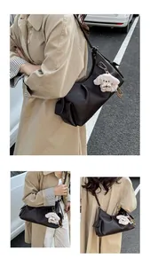 Detail of a dark brown pleated shoulder bag with a cute plush dog charm accessory