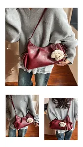 Detail of dark red pleated pillow bag with glossy finish and white plush dog charm