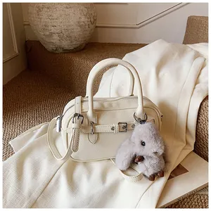 Detail of off-white lychee texture bag with decorative buckle and cute rabbit pendant