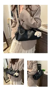 Detail of black pleated leather crescent bag featuring a cute plush puppy charm accessory