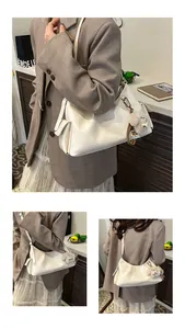Detail view of large cream commuter bag with decorative buckles and plush dog pendant