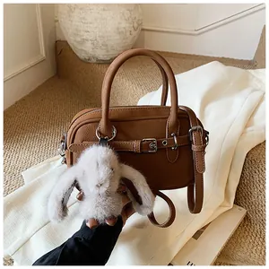 Close-up of brown Boston bag with pebbled leather texture and cute rabbit plush charm