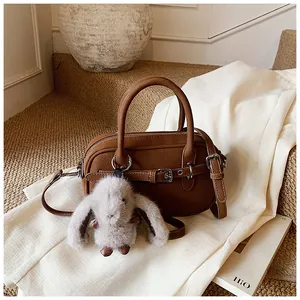 Detail of vintage brown textured leather handbag with plush rabbit charm and strap