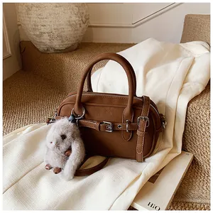 Close-up of dark brown pebble leather handbag with retro buckle and plush rabbit charm