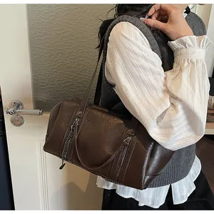 Detail view of dark brown retro Boston bag with metallic zippers and chain ornament