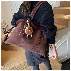 Detailaufnahme der braunen Wildledertasche mit Metallnieten und Donut-Anhänger