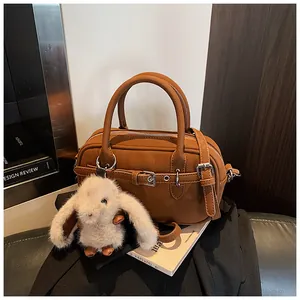 Detailed shot of brown pebble leather handbag featuring belt buckle and rabbit charm