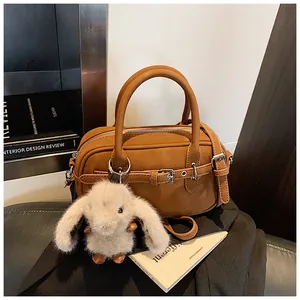 Detail of brown litchi pattern leather bag with a cute white plush bunny charm