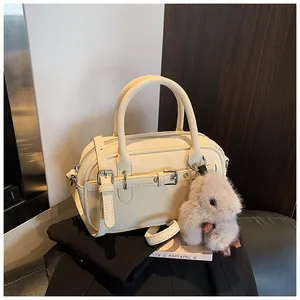 Detailed view of cream-colored satchel with pebble texture and plush bunny charm