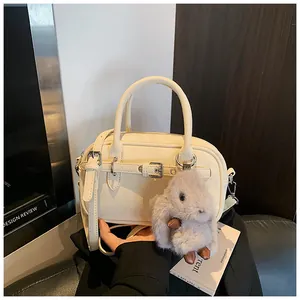 Detail of off-white lychee texture faux leather bag with bunny charm and strap