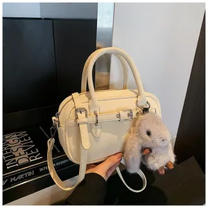 Detail of off-white lychee grain leather handbag with silver hardware and plush bunny charm