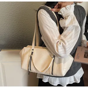 Detail of cream Boston bag showing leather texture, dual straps and metallic zipper accents