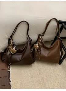 Detail view of two brown faux leather hobo bags with bear charms and fringe accents