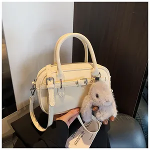 Detail of cream white leather satchel with litchi texture and cute plush bunny charm